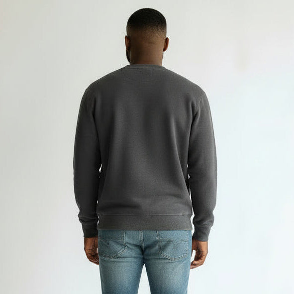 Person wearing a dark gray sweater and light blue jeans on a white background